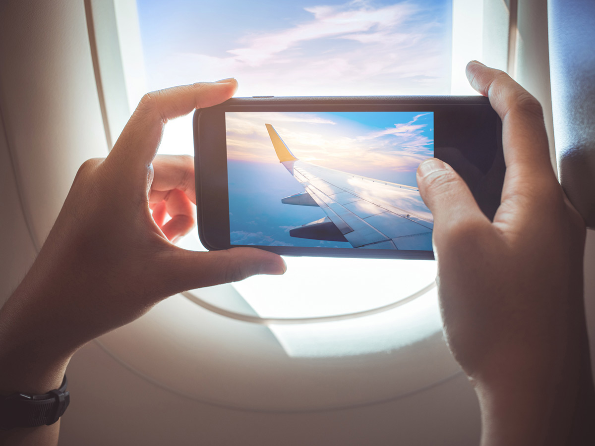 person taking a photo out of the plane window while in flight