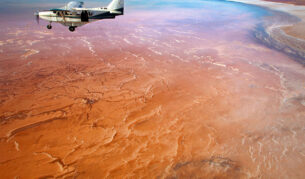 a small plane flies over Lake Eyre/Kati Thanda