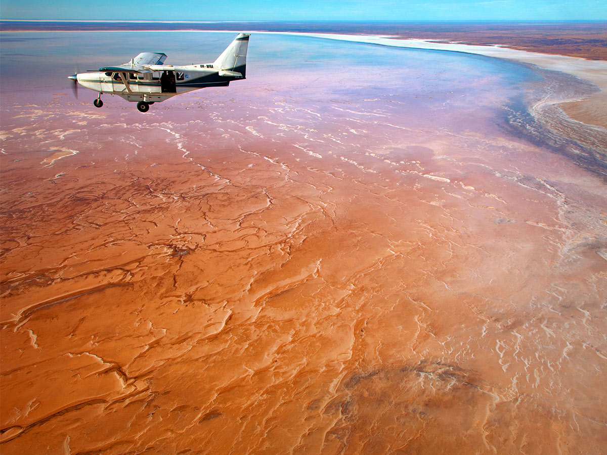 a small plane flies over Lake Eyre/Kati Thanda