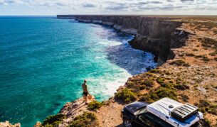 Aerial view of car parked with camper and young man overlooking the Great Australian Bight. Captured while crossing the Nullarbor.