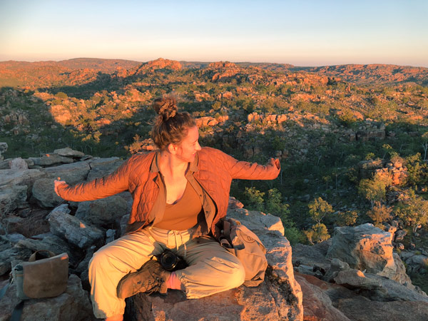 Imogen Eveson sitting atop a rock in Bullo at sunrise