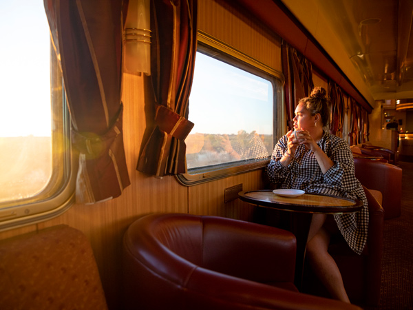 a woman looking out the window in the gold service lounge of The Ghan