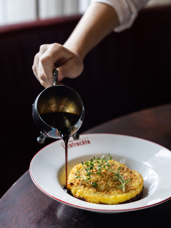 pouring sauce over a dish at Bouillon l'Entrecôte, Sydney