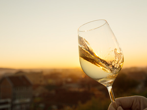 A person raising a glass of Chardonnay against a glowing Western Australia sunset.
