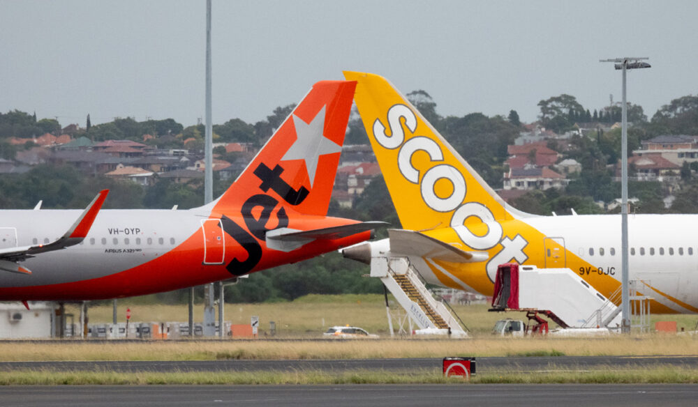 A Jetstar Airbus A321-251NX plane, registration VH-OYP, taxiing at Sydney Kingsford Smith Airport for departure as flight JQ37 to Denpasar. She is passing a Scoot Boeing B787-9 plane, registration 9V-OJC