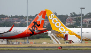 A Jetstar Airbus A321-251NX plane, registration VH-OYP, taxiing at Sydney Kingsford Smith Airport for departure as flight JQ37 to Denpasar. She is passing a Scoot Boeing B787-9 plane, registration 9V-OJC