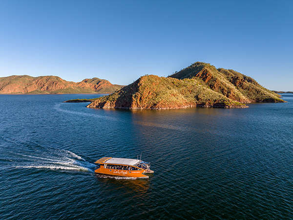 A boat glides across the expansive waters of Lake Argyle, surrounded by the breathtaking landscapes of the Kimberley. As part of the Discovery Holiday Parks experience, this unforgettable journey offers adventure and relaxation.