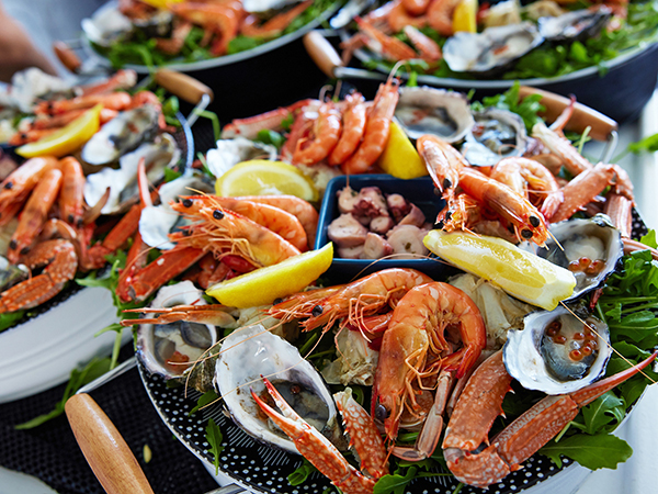 A table filled with plates of crab, crayfish, and scallops.