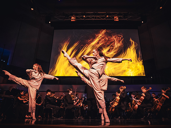 Dancers performing gracefully, accompanied by a live orchestra.
