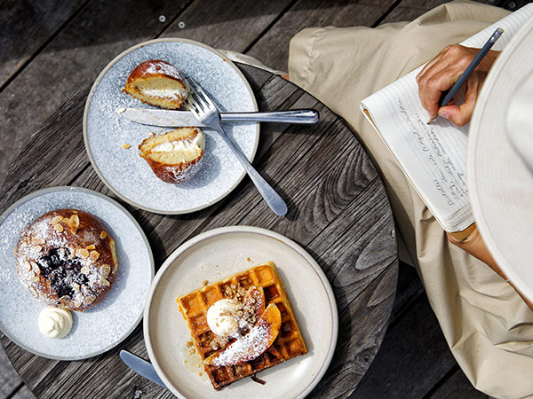 woman writing in notebook next to a table of food at Saddles, Central Coast food