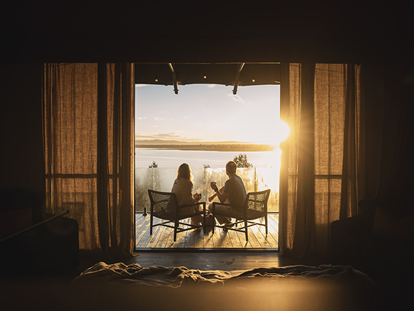 Bathed in warm light, a couple watches the sun dip beyond the horizon.