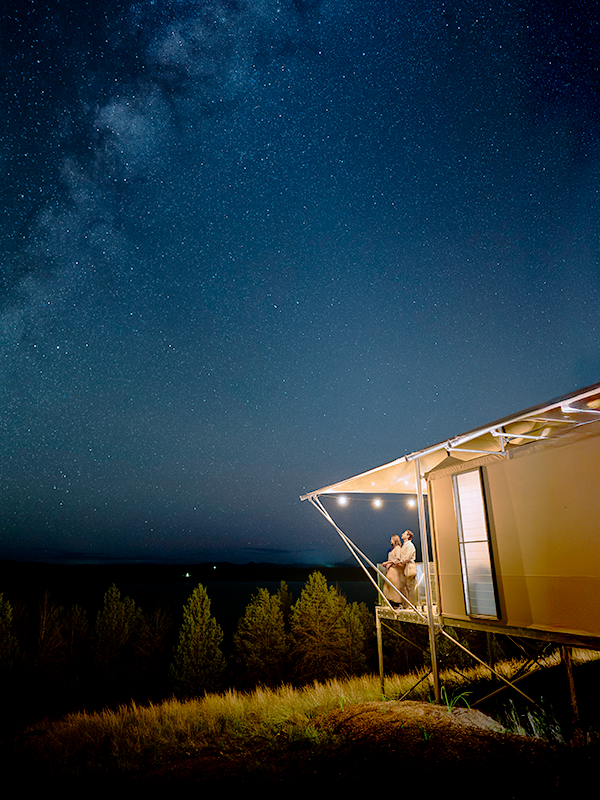 A couple gazes up at a sky ablaze with stars at Wilderluxe.