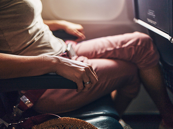 person holding onto chair armrests in plane