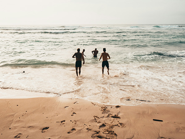 a group of people running into the ocean from a beach