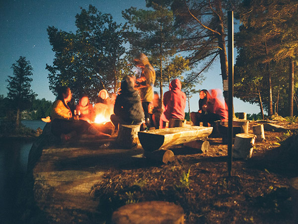 group of friends around a campfire at night