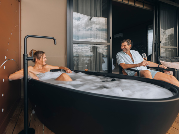 Couple on the deck enjoying the bathtub on the patio of Wilderluxe glamping tent