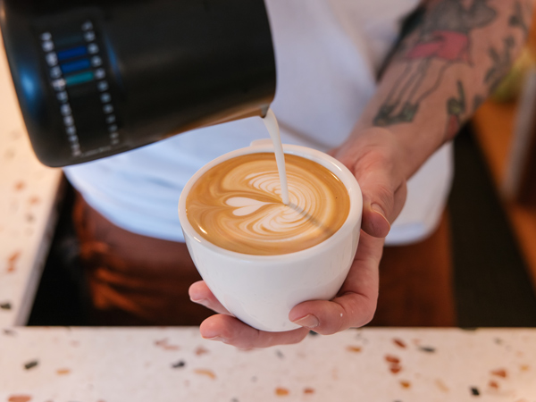 pouring milk over coffee at Solstice cafe, Sydney