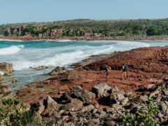 Two people walking on the rocky shoreline near the ocean. Light to Light walk