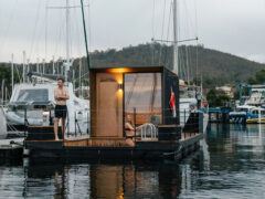 A man and woman standing on a floating sauna.