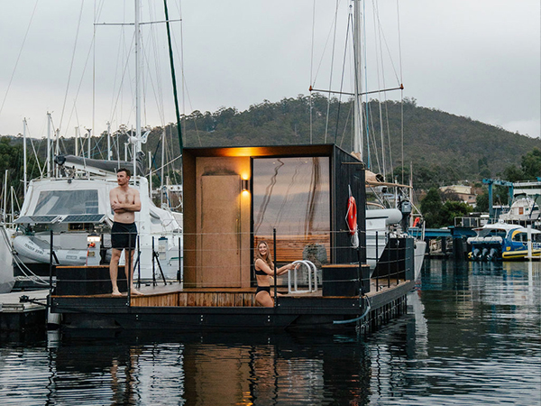 A man and woman standing on a floating sauna.