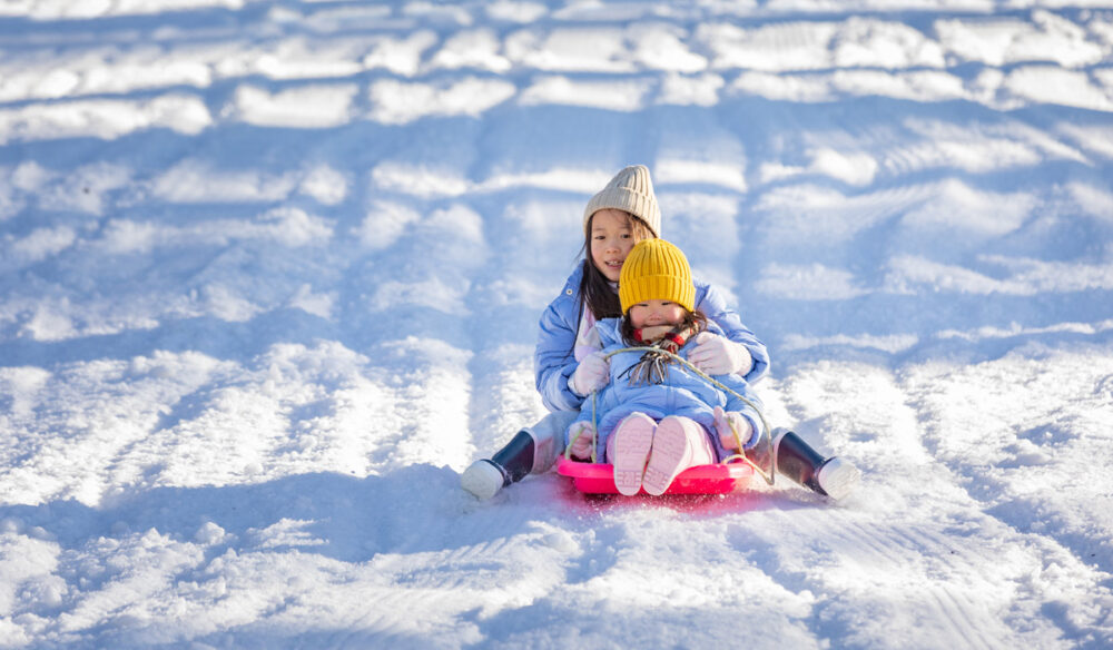Two children tobogganing at Corin Forest
