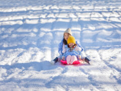 Two children tobogganing at Corin Forest