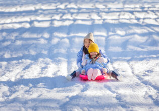 Two children tobogganing at Corin Forest