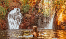 Surrounded by lush forest, a woman cools off in Florence Falls, just one of many incredible things to do in the Northern Territory.