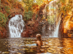 Surrounded by lush forest, a woman cools off in Florence Falls, just one of many incredible things to do in the Northern Territory.