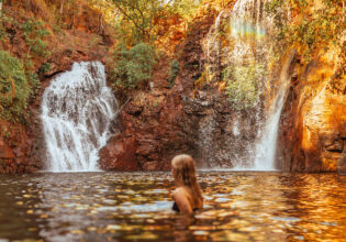 Surrounded by lush forest, a woman cools off in Florence Falls, just one of many incredible things to do in the Northern Territory.