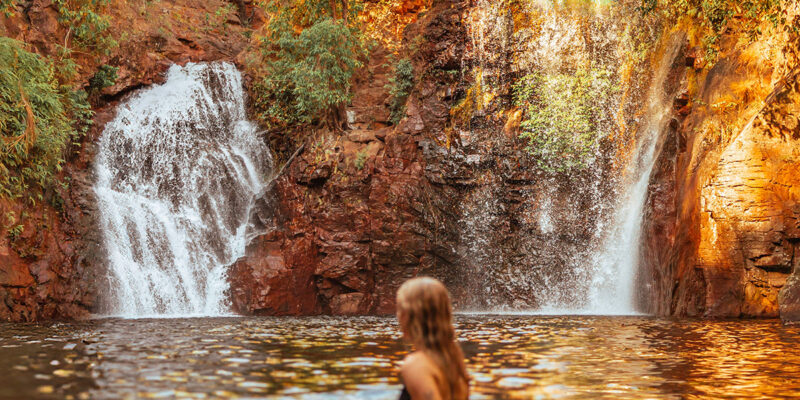 Surrounded by lush forest, a woman cools off in Florence Falls, just one of many incredible things to do in the Northern Territory.