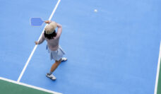 top view of woman playing pickleball, holding paddle to return ball in pickleball court