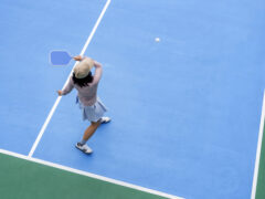 top view of woman playing pickleball, holding paddle to return ball in pickleball court