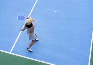 top view of woman playing pickleball, holding paddle to return ball in pickleball court